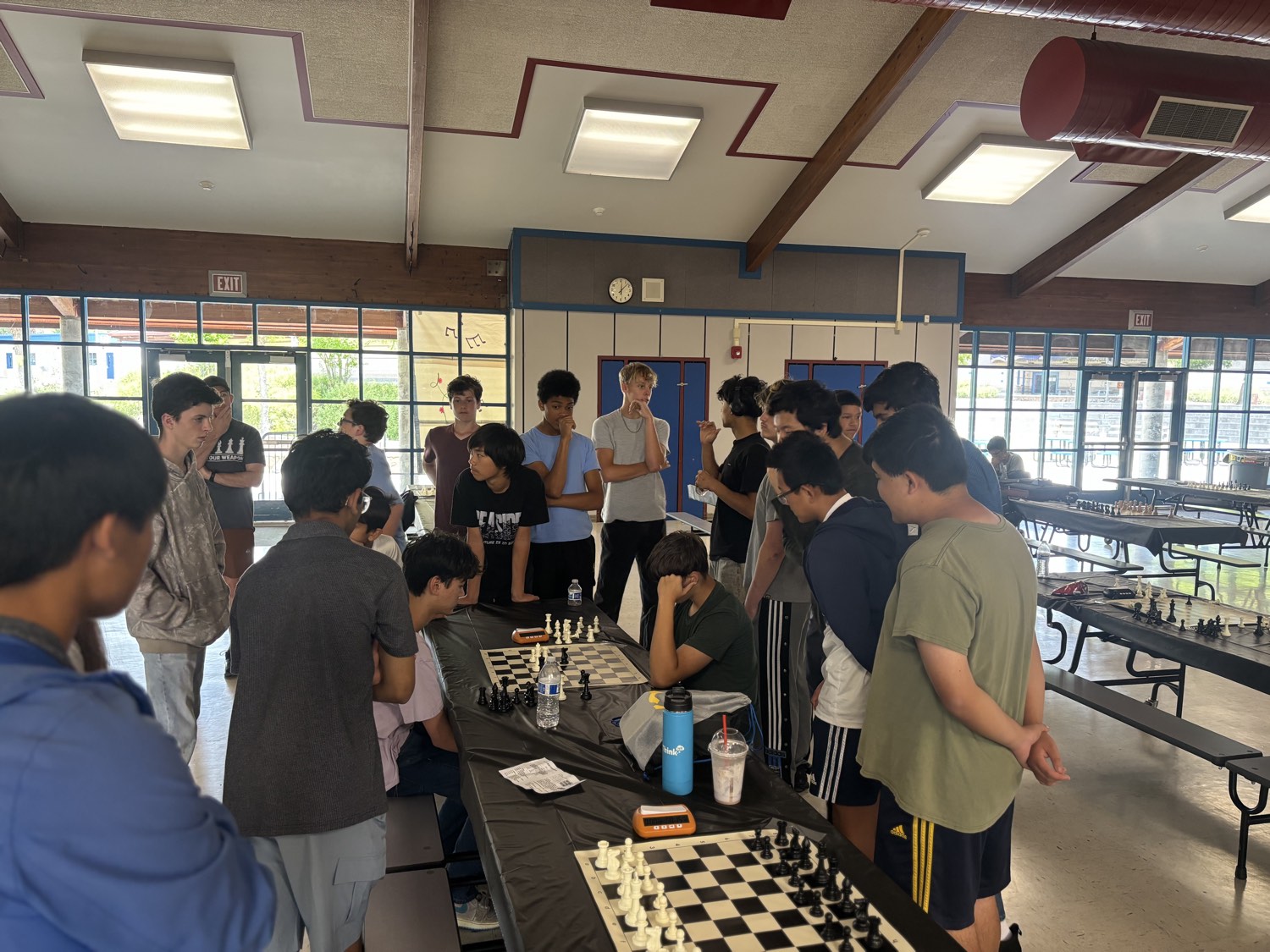 Players and spectators gathered around a board analyzing a game after their match